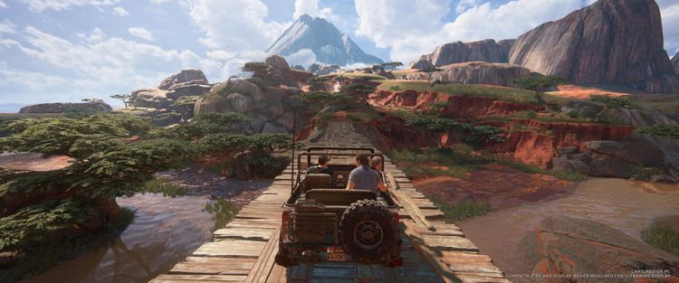 Gameplay scene from Uncharted: Legacy of Thieves Collection featuring a character driving across a wooden bridge in a scenic landscape.