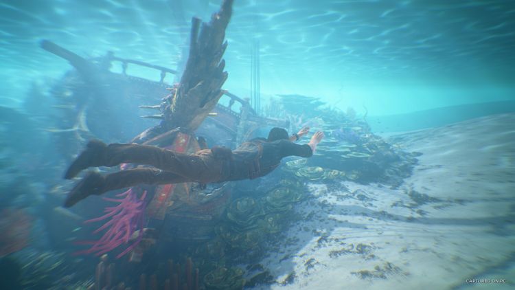 Character diving underwater near a sunken ship with vibrant coral in UNCHARTED: Legacy of Thieves Collection.