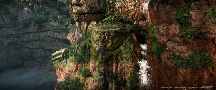 Heroic character climbing a moss-covered cliff with a waterfall in the Uncharted: Legacy of Thieves Collection.